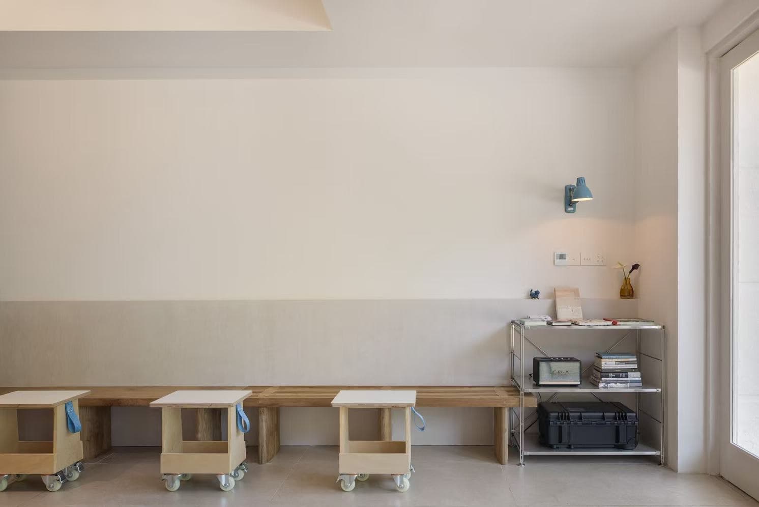 The slatted bench along the wall, stools on castors and a steel bookshelf