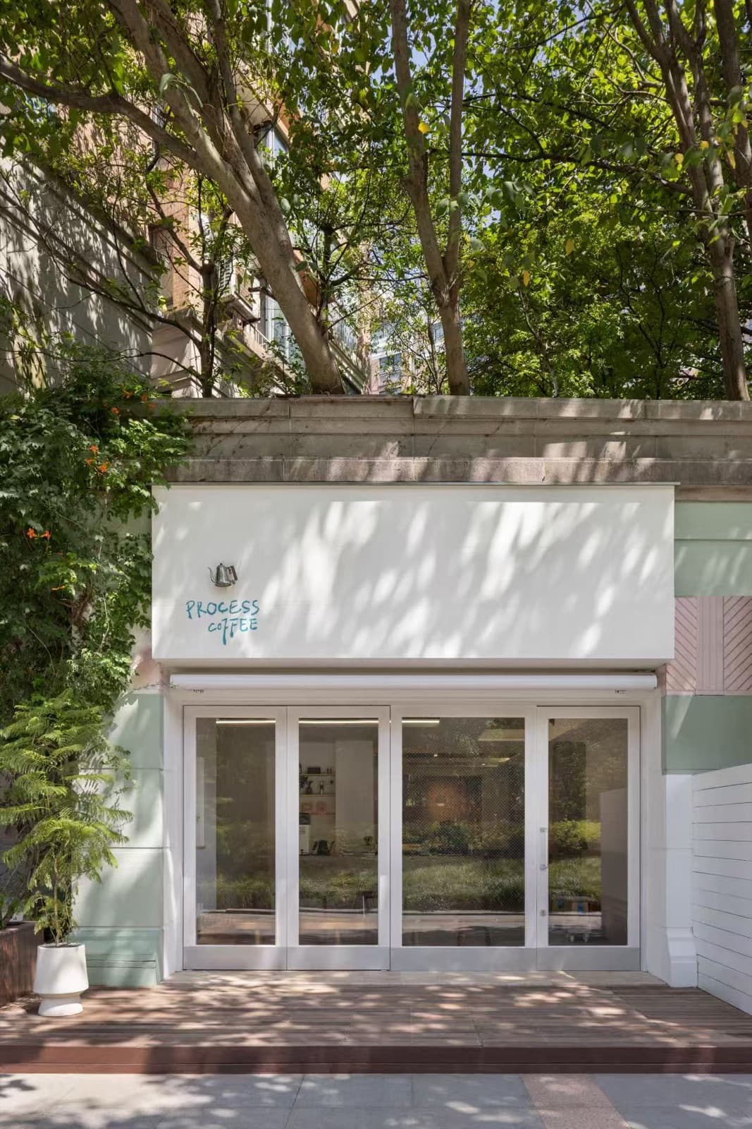 The shopfront by day, four glass doors closed, a wooden deck in front