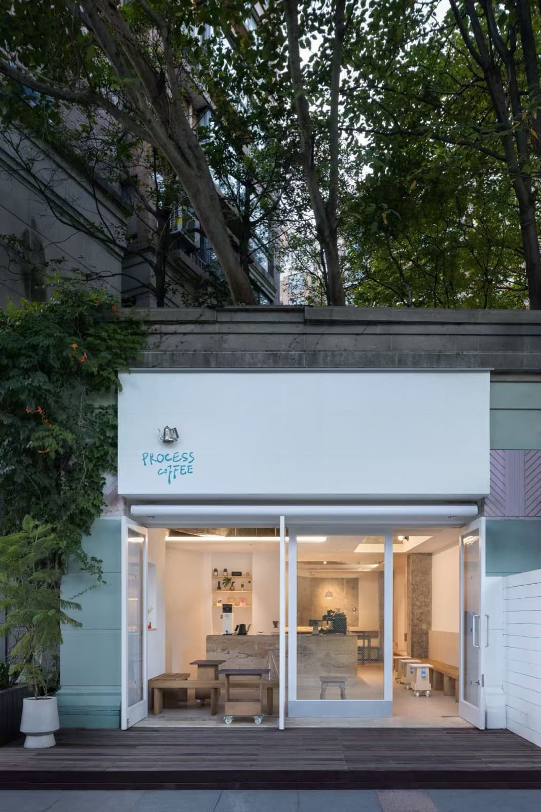 The shopfront at dusk with every door open and the lights on inside