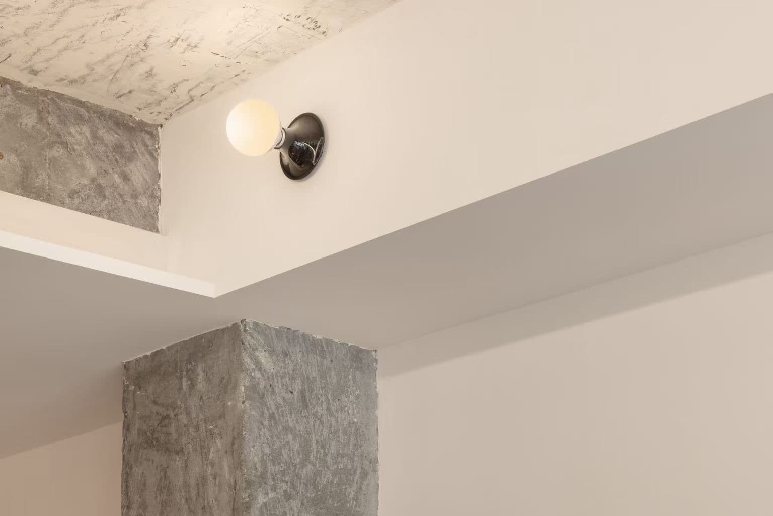 A globe wall light above a concrete column