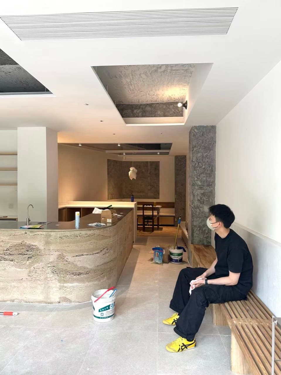 完工前的店里,石色的吧台、木条长凳和切开的顶面,一个人坐在长凳上