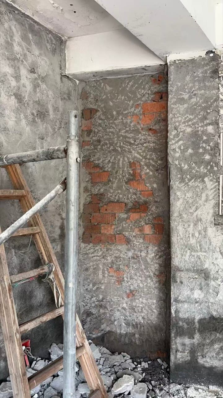 凿开的墙面露出红砖和混凝土柱,旁边是一架梯子