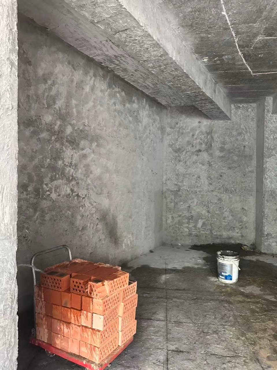 拆完以后的毛坯房间,地上有一摞红砖和一只桶