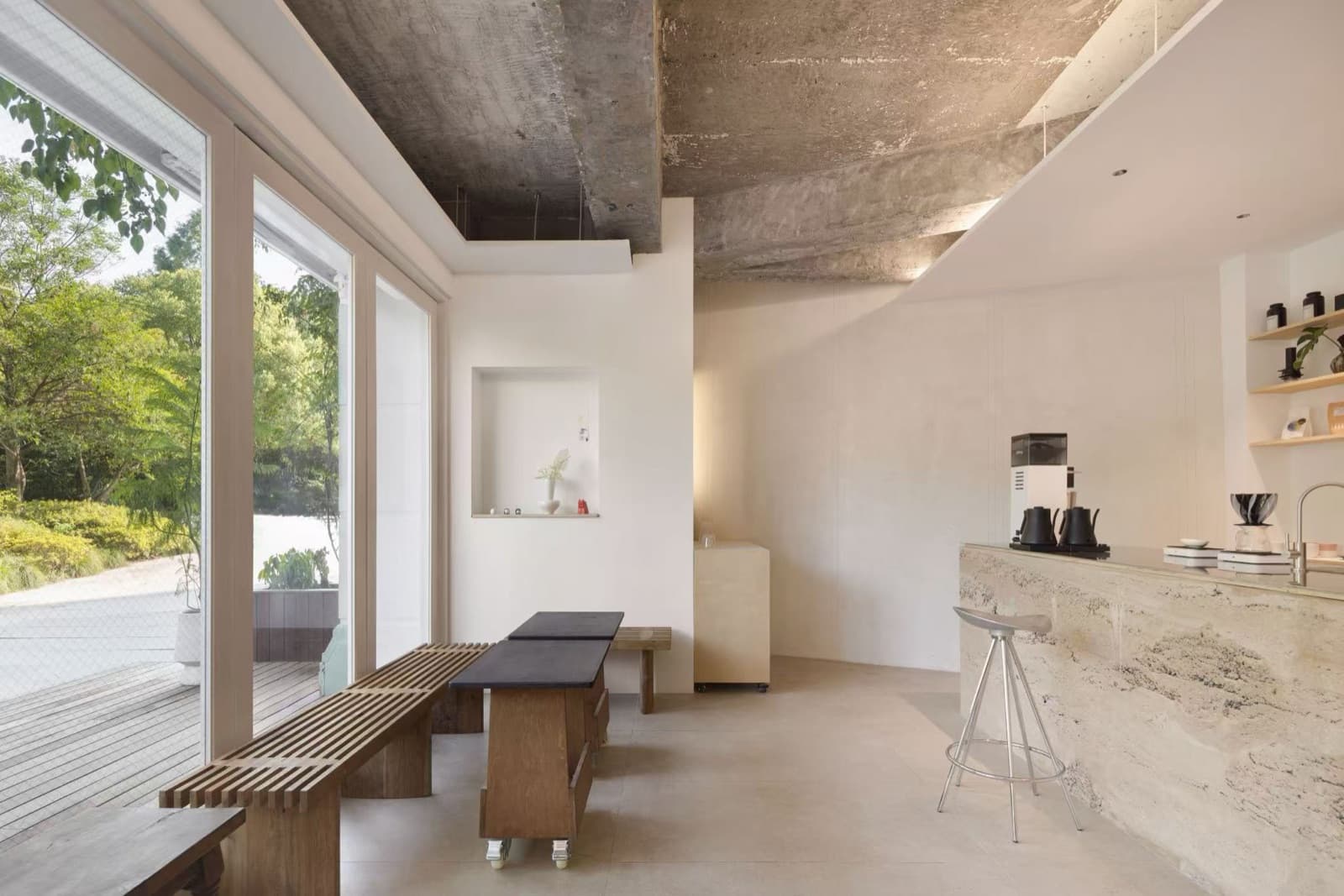 Benches and small tables by the street windows, the stone-coloured bar and a metal stool on the right